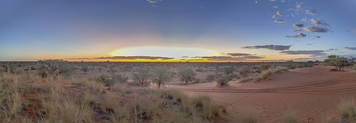 Panoramic picture over the Namibian Kalahari in the evening at sunset with blue sky and light clouds in summer