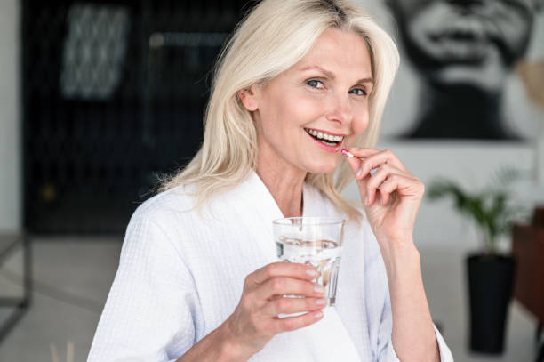 istock Smiling middle aged woman taking vitamin supplement pill 2129719481