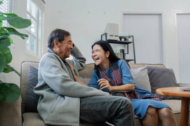 istock Older couples sit and chat and head over each other relaxed and happy on sofa at home on weekday in comfortable 2129719990