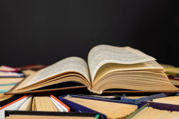istock Open book and old books in library on dark background 2129723686