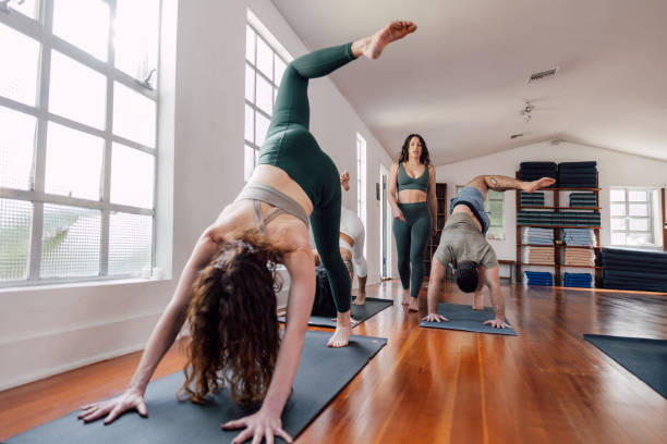 Small mixed class doing exercises at a modern yoga studio gym. Small group of people men and women of different ages practicing mindfulness and yoga lesson.