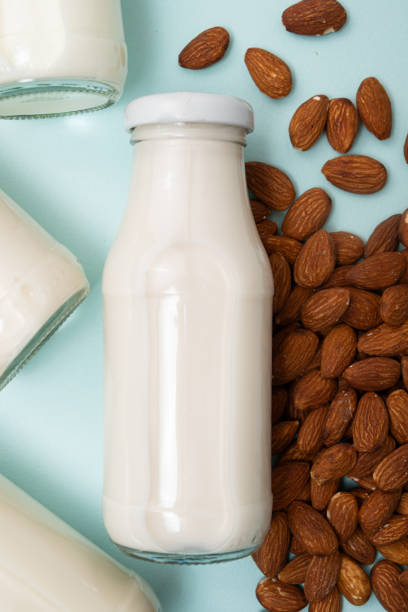 istock Almond nut milk in a glass bottle on a blue background top view. 2129763294