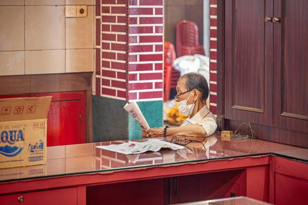 Vihara Gunung Timur Temple, Medan, Sumatra, Indonesia - January 16th 2024: Employed man reading his newspaper in the Chinese Buddhist - Confucian temple just before the Chinese new year