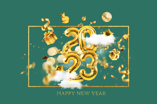 Golden Metallic Balloons 2023 fly with golden gifts, confetti, disco ball, bunnies and clouds on a green background. Happy New Year 2023, a creative idea. Golden New Year luxury card