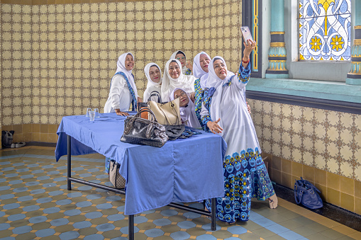 Masiid Raya Al-Mashun, Medan, Sumatra, Indonesia - January 16th 2024:  A group of women having fun and taking selfies after the prayer in the grand mosque