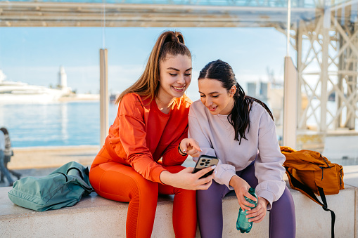 Two beautiful female friends checking fitness activity after jogging outdoors in Málaga in Spain.