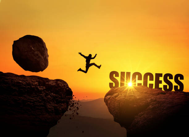 istock Businessman runs from a falling stone on a mountain and jumps over a cliff at sunset. Success, finance and business. Creative idea for success. Rockfall and danger 2129781178