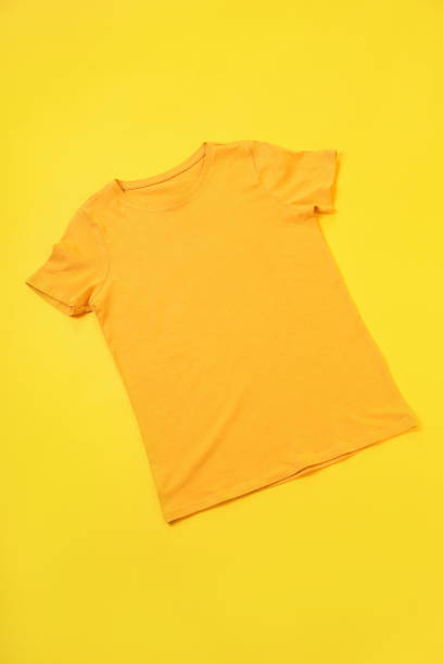 istock Orange t-shirt with space for print on yellow background 2129820615