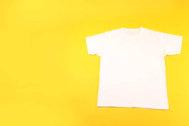 istock White t-shirt with space for print on yellow background 2129827619