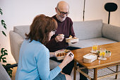 A senior couple shares a cozy moment at home, eating Asian takeout food