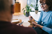 A senior couple shares a cozy moment at home, eating Asian takeout food