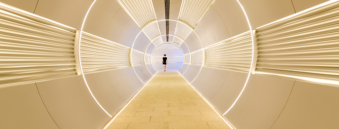 Woman walking in corridor tunnel.