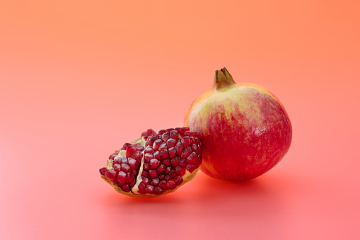 Whole pomegranate and pomegranate piece on white background.