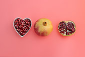 Pomegranate seeds in heart shape bowl on red background