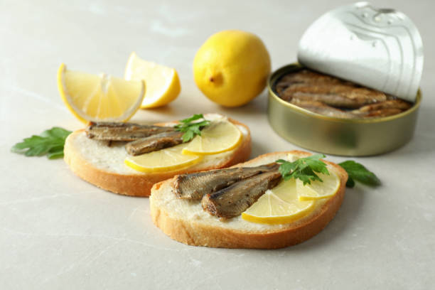 istock Sandwiches with sprats and ingredients on light background 2129859909