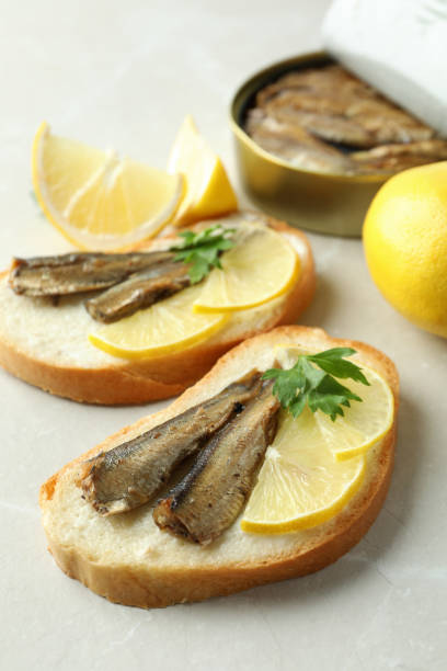 istock Sandwiches with sprats and ingredients on light background 2129860967
