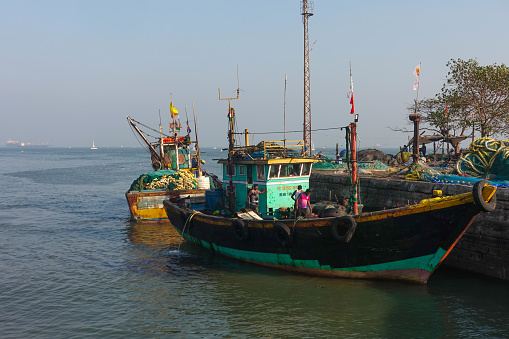 Fishermen working on their fishing boats moored in Sassoon Docks harbor which is one of the oldest docks in Mumbai, It is one of the largest fish markets in Mumbai City