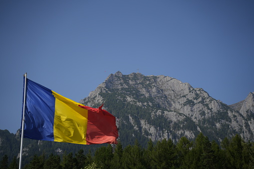 The flag of Romania waving in front of a mountain range