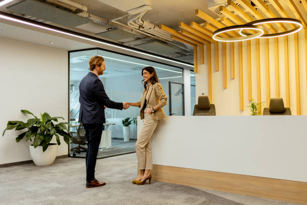 istock Warm Handshake Between Colleagues In Modern Office Lobby Under Ambient Lighting 2129868968