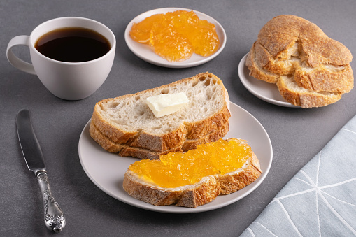 Sandwiches with apricot jam and a cup of coffee on a gray background. Breakfast concept.
