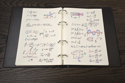 The image displays an open notebook filled with detailed physics equations and diagrams, annotated with colored pens, suggesting an educational or study setting.
