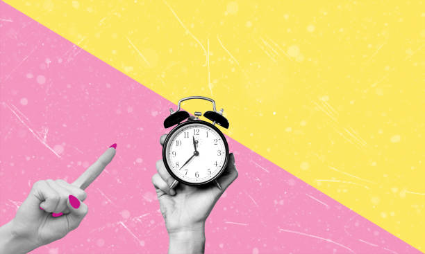 istock Human hand holding an alarm clock on a pink and yellow background, with copy space. 2129907963