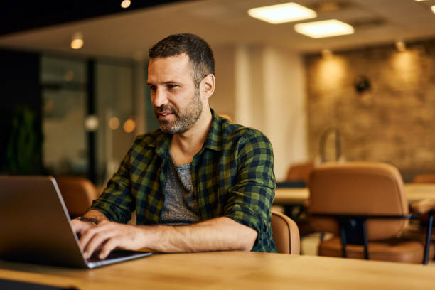 istock A smiling businessman typing some emails over the laptop, working at the office. 2129917840