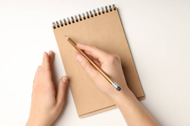 istock Female hands write in craft notebook on white background 2129920999