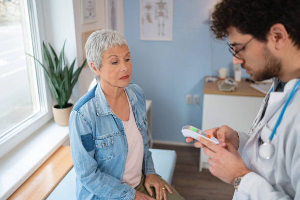 istock Doctor using digital thermometer to measure senior female patient's temperature 2129932052