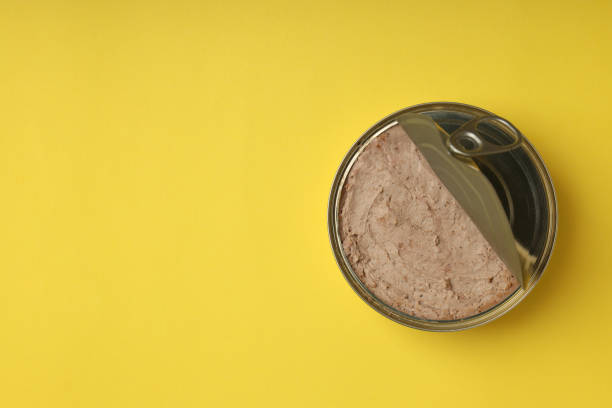 istock Tin of pate on yellow background, space for text 2129941570