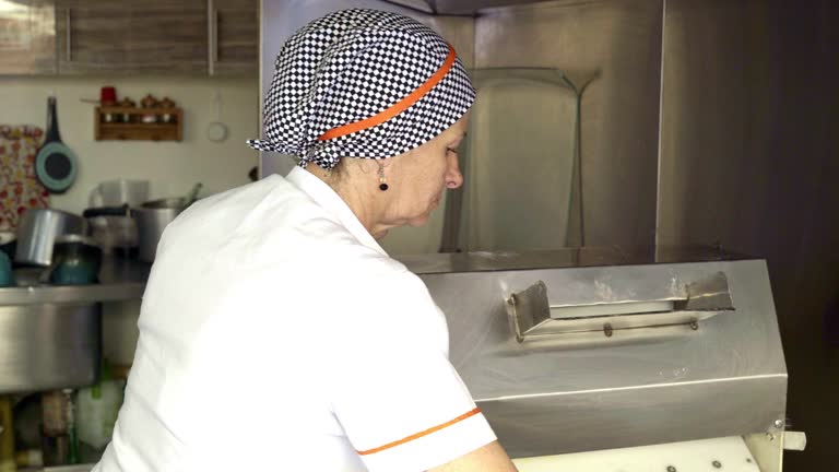 Latin woman is inside the kitchen of a small empanada food business