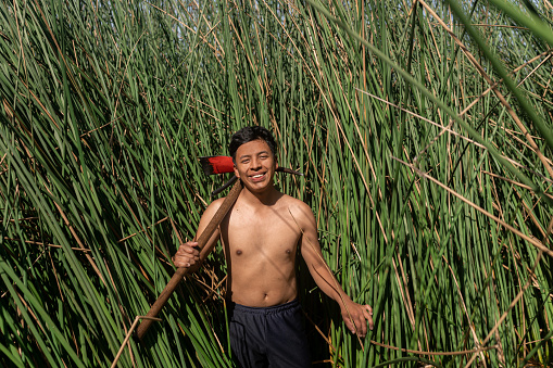 Portrait of a latin happy male volunteer reforesting an area planting reeds under the sun. Guatemala