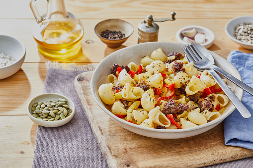 Healthy American - Italian beef pasta, made from fresh beef, zucchini, onion, garlic and red pepper, served on a modern ceramic plate, on a light wooden kitchen or restaurant table, representing a healthy lifestyle, body care and wellbeing, table view with a copy space