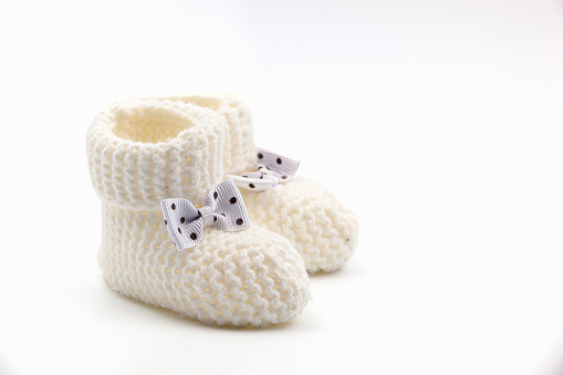 White crochet baby booties with black polka dot bows isolated on a white background. Handmade baby booties. Photo in high quality