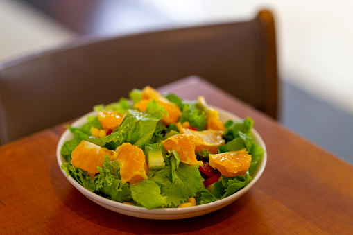 Orange Fruit Salad Served In White Ceramic Dish On Wood Table