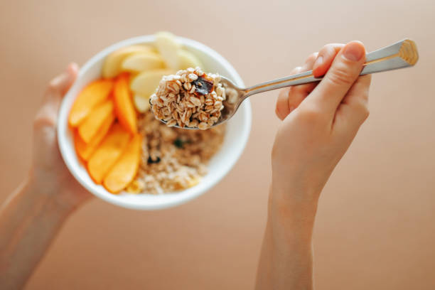 istock Close up cereal fruit nutritious breakfast in female hands unrecognizable, spoon with food in hand. 2130148238