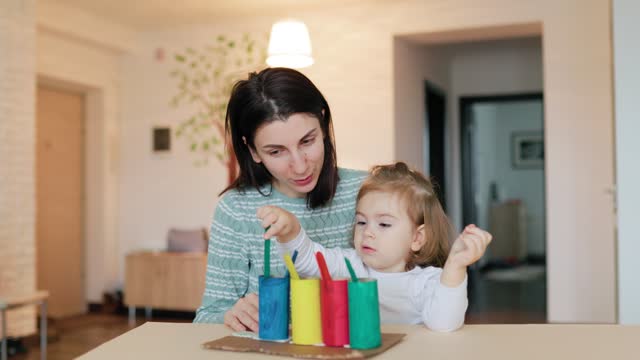 a young woman with a child teaches her daughter at home.
