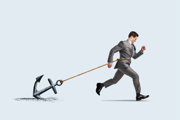 istock Businessman Struggling To Run While Dragging An Anchor 2130266938