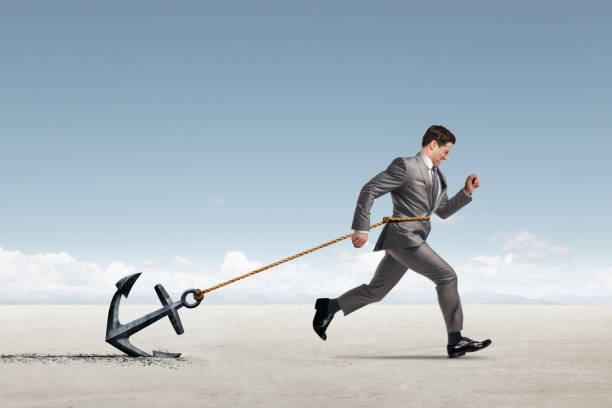 istock Businessman Struggling To Run While Dragging An Anchor 2130267303