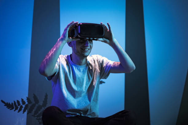 istock Man with VR glasses sitting on the virtual reality escape room floor 2130300672