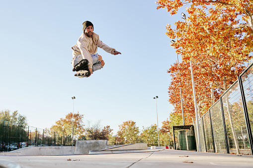 young male roller skater jumping and doing a trick with his inline skates.