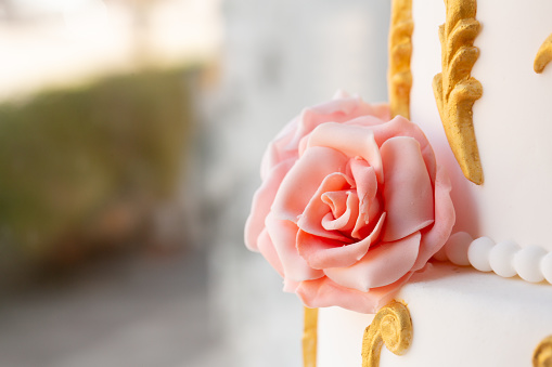 a beautifully crafted fondant rose adorns a wedding cake, enhanced by ornate gold trim, epitomizing luxurious celebration
