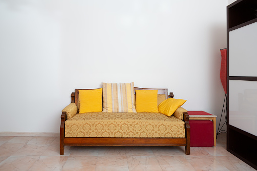 a classic wooden sofa with yellow cushions brings warmth to a cozy corner, exuding vintage charm and comfort