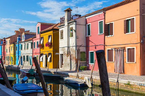 Разноцветные красочные дома в Венеции на острове Бурано. Узкий канал с моторными лодками вдоль домов. Летний солнечный день. Выборочная фок