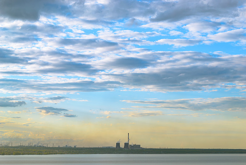 Thermal power plants and other factories stand on the shore of the lake under the evening sky