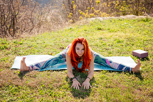 Beautiful mature woman practicing yoga on yoga mat in nature