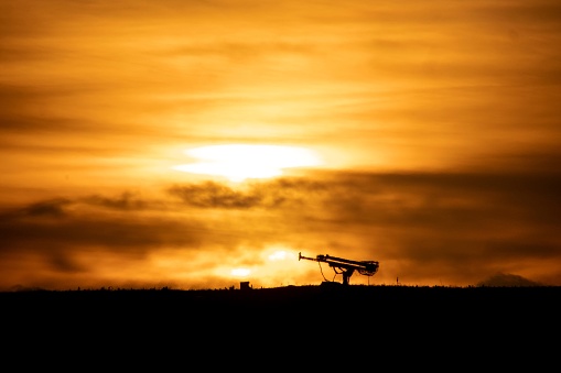 Machinery resembling gun emplacement silhouetted against the sunset on a hill in Essex