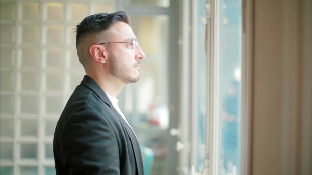 istock Pensive man by glass block window 2130383504