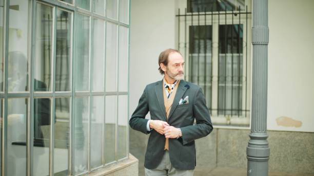 istock Refined man buttoning jacket near urban glass facade. 2130383514