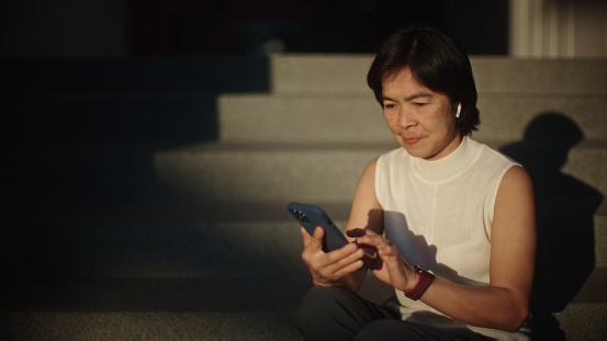 Asian woman using smartphone outdoors in the morning.